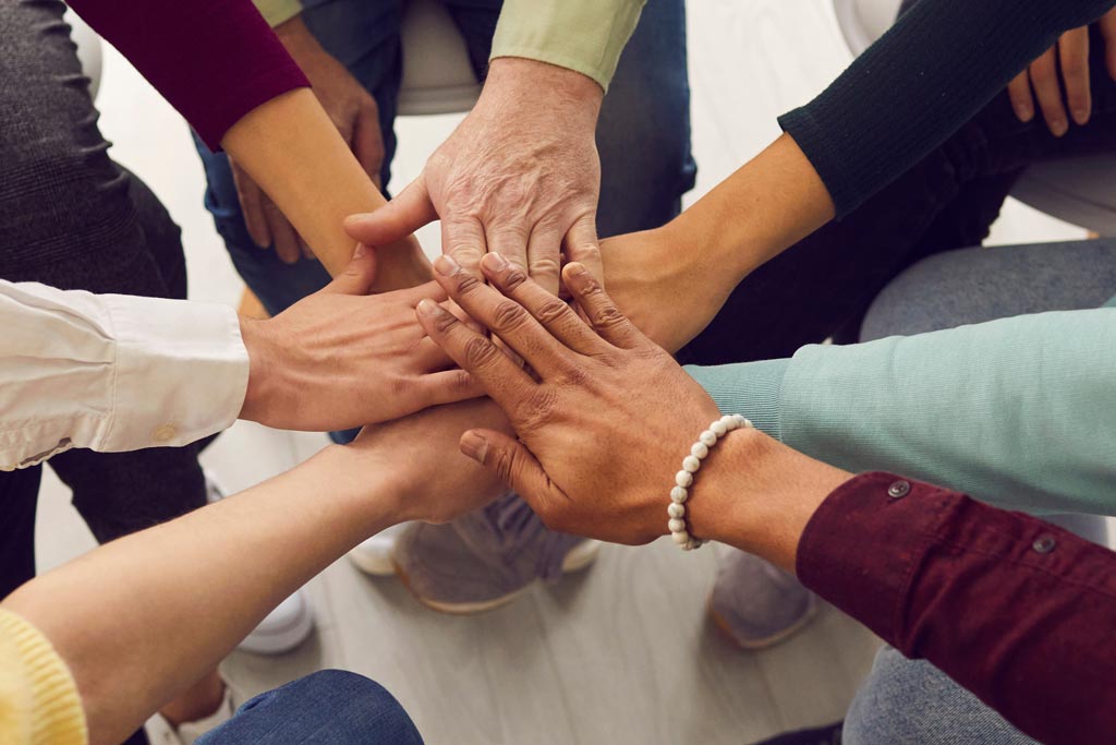 Stack of hands symbolizing teamwork and unity.