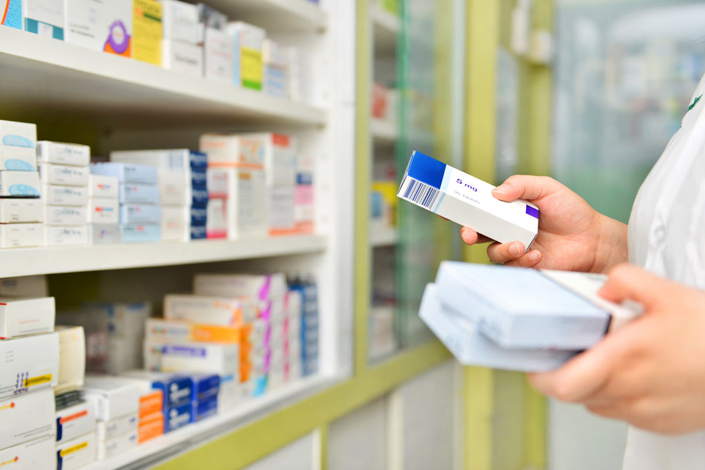 Person holding medications in pharmacy.