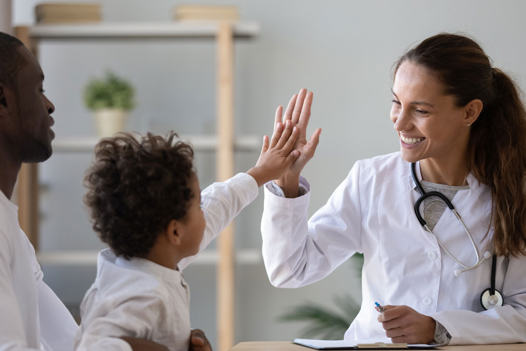 Primary care doctor high-fiving a toddler.