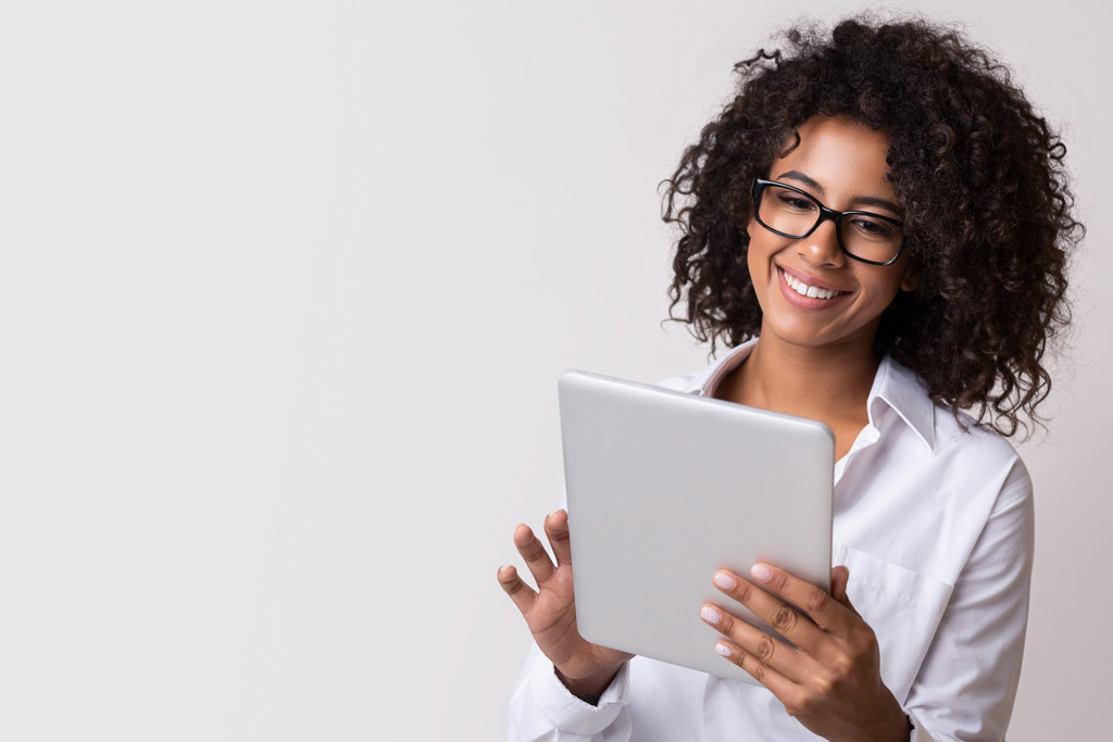 Young woman smiling and holding a tablet.